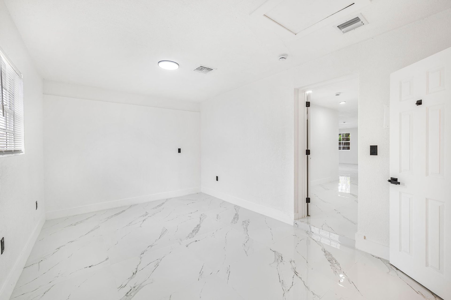 White kitchen with stainless steel appliances, white cabinets, and white countertops.