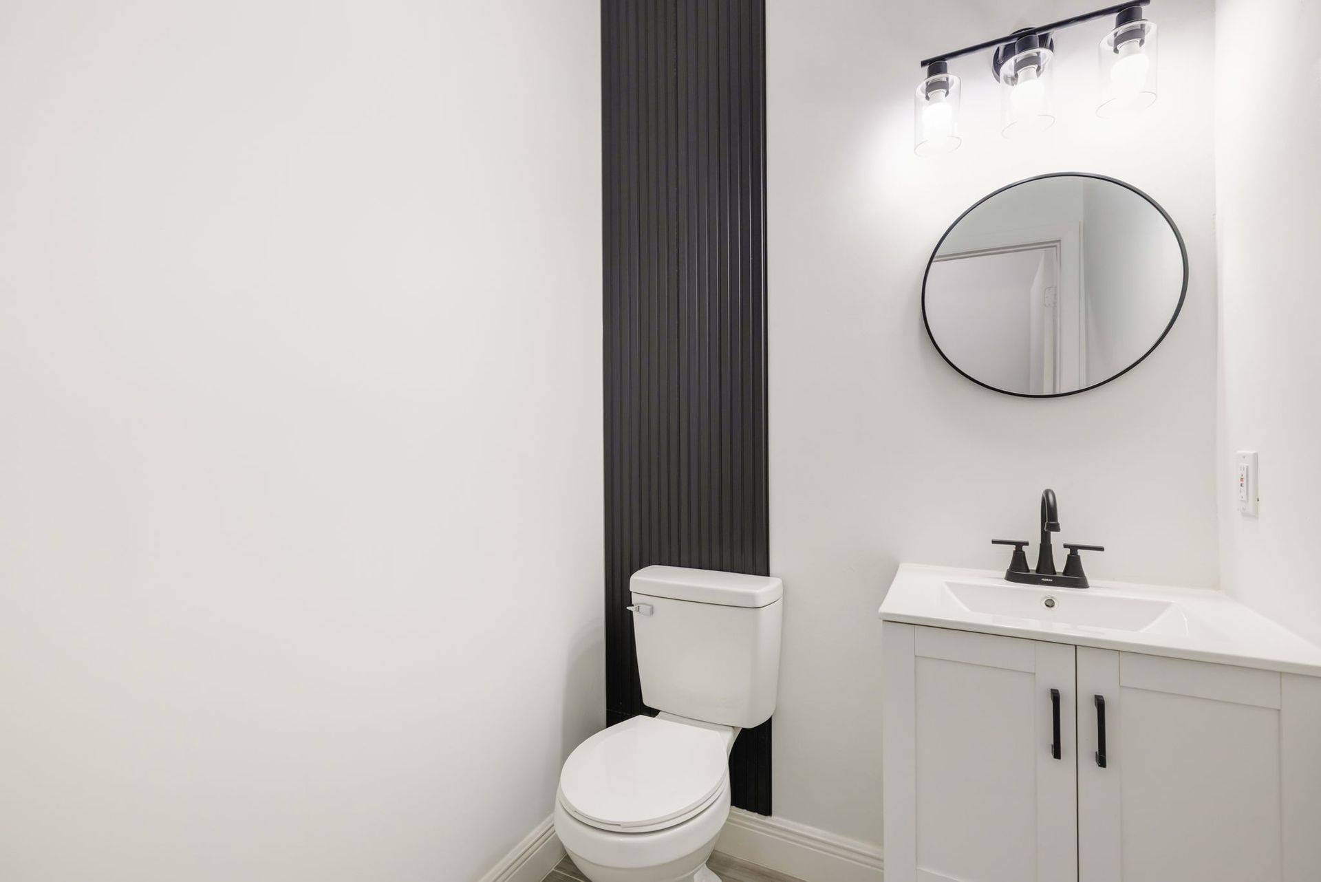 A bright, modern open-concept living area with light wood floors, a white kitchen island, and a sliding glass door patio.