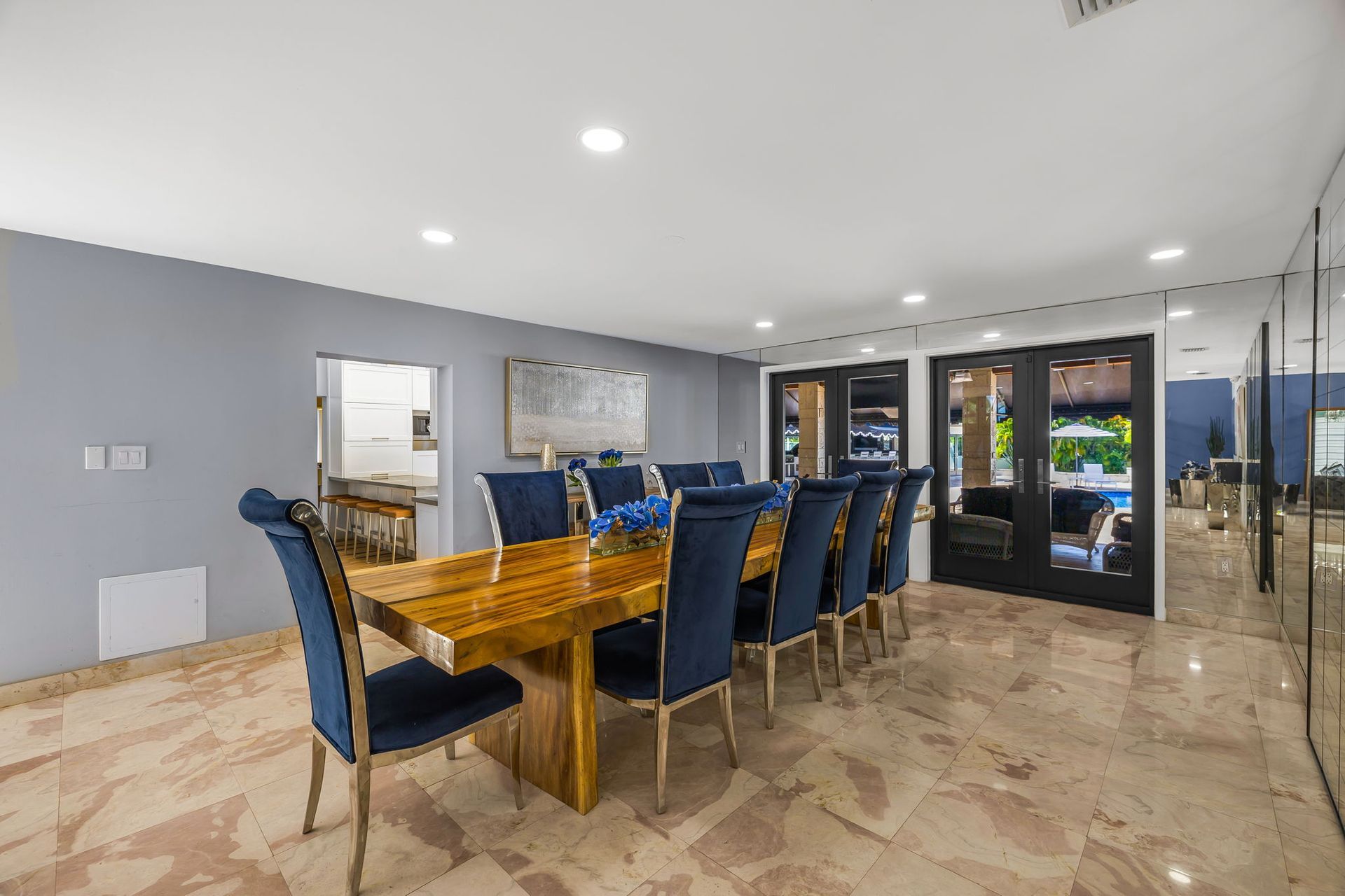Formal dining room with a long, wooden table and blue velvet chairs.