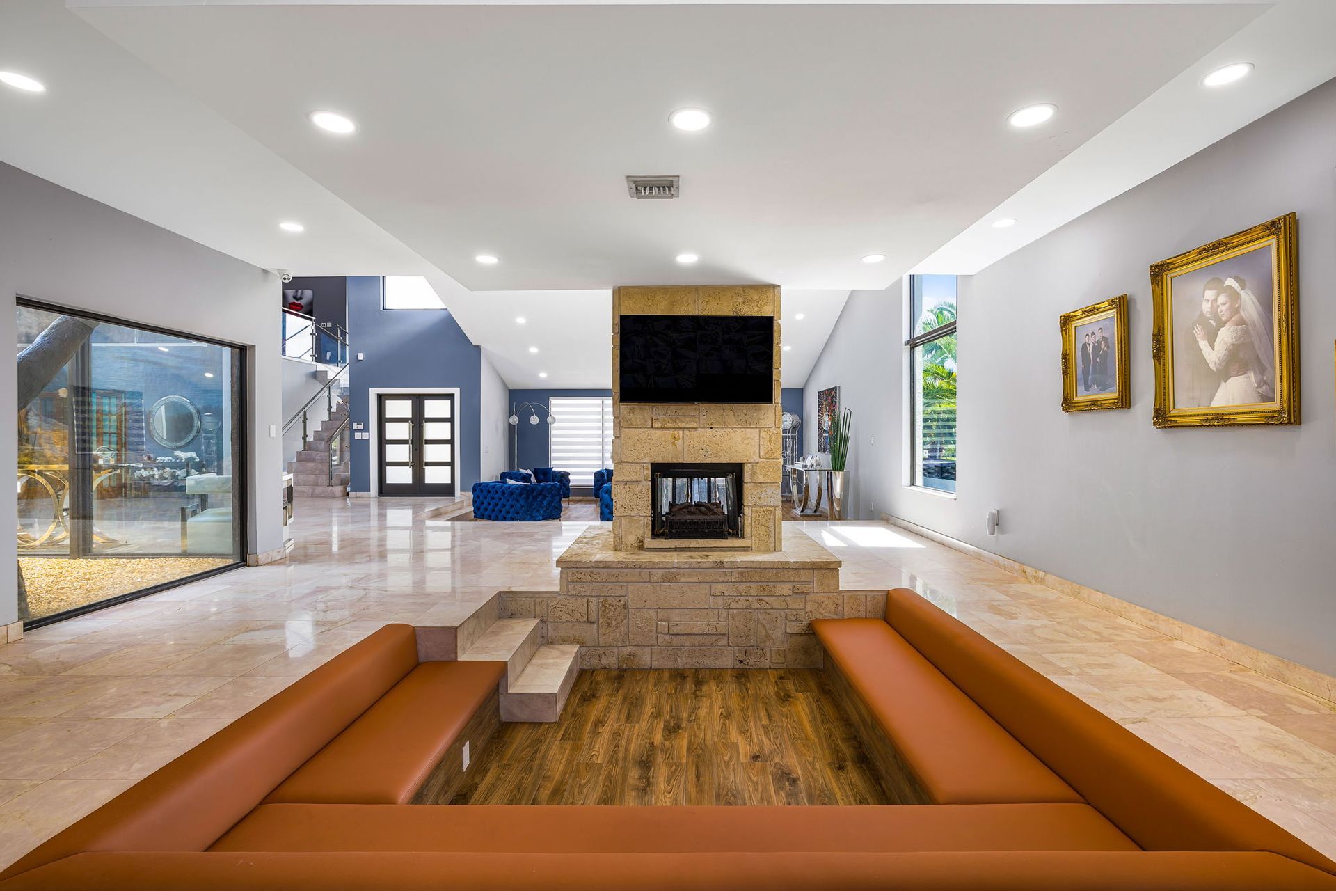 Modern living room with fireplace, sunken seating, and marble floors.