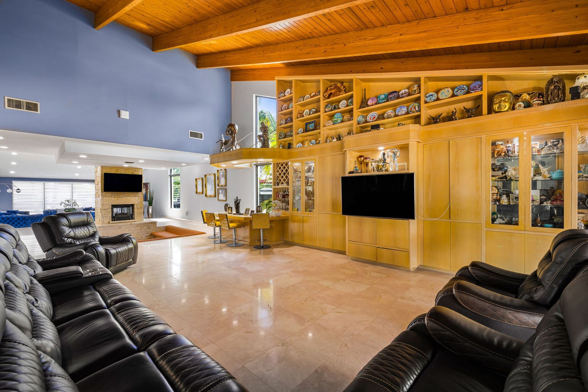 Spacious living room with leather recliners, a bar, and display shelves with sports memorabilia.