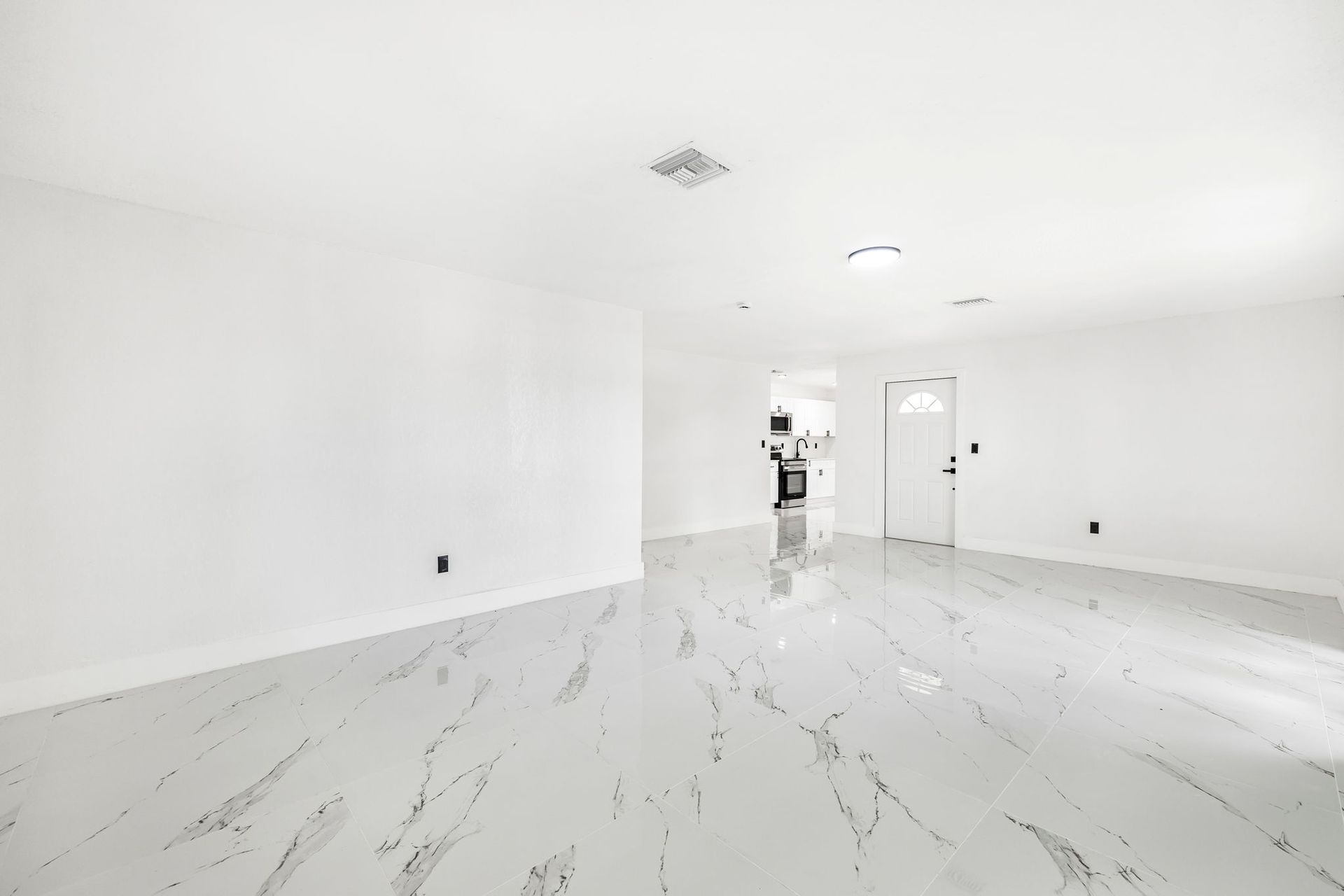 Empty white room with glossy marble floors, windows, and white walls.