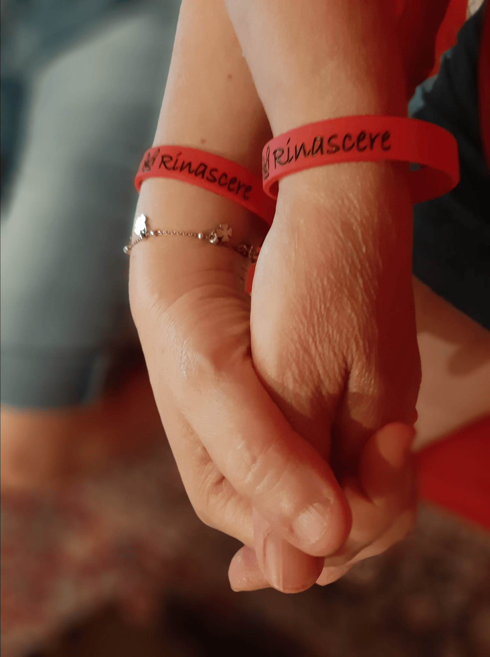 Mani intrecciate che indossano i Braccialetti del Centro Anti Violenza Fammi Rinascere