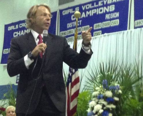 A man stands in front of a sign that says girls volleyball champions