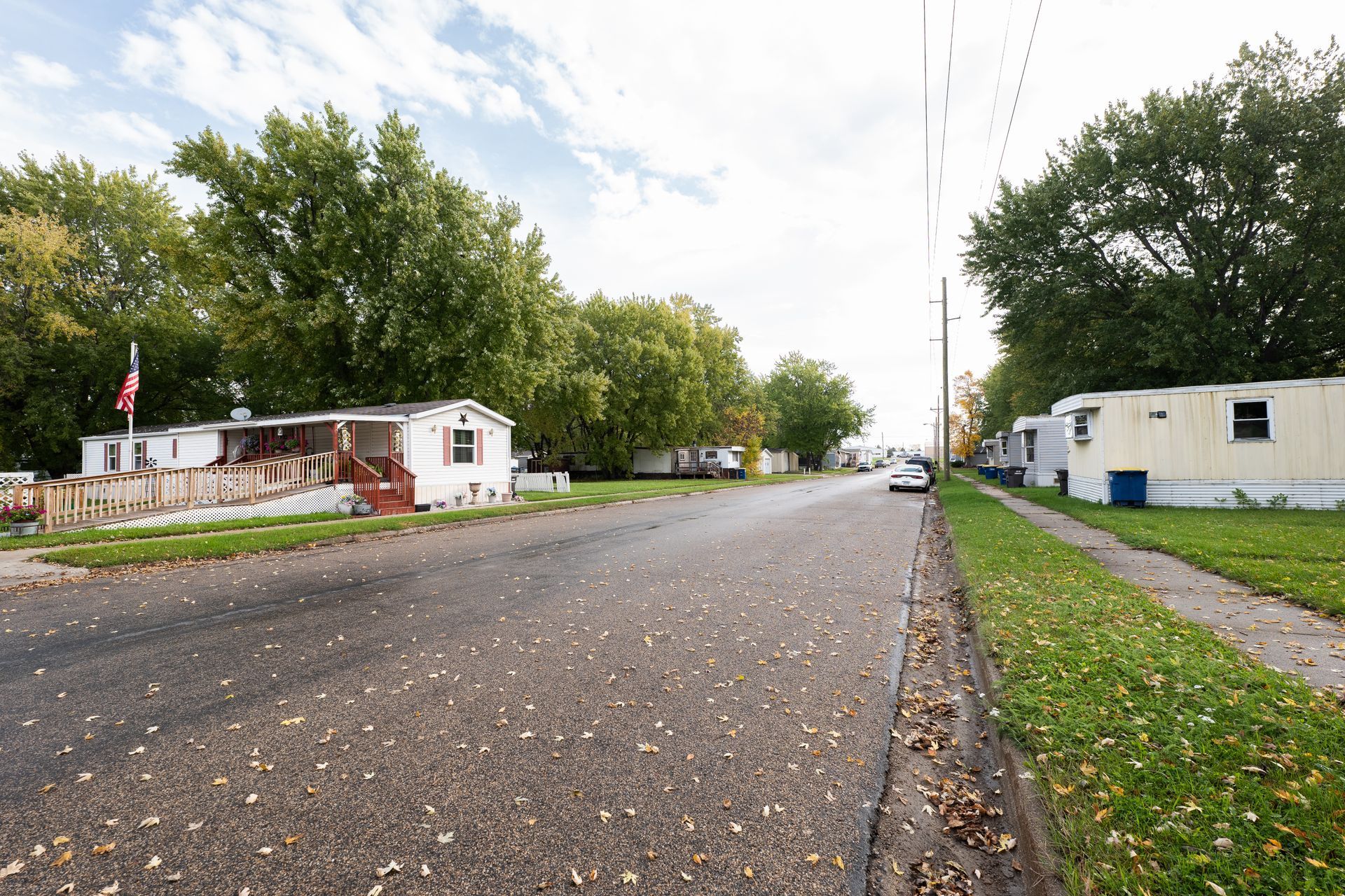 The sun is setting over a grassy field with a fence in the foreground.