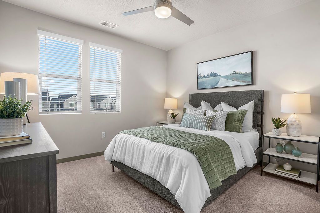 Bedroom in a modern apartment with a queen bed, two nightstands, and large windows.