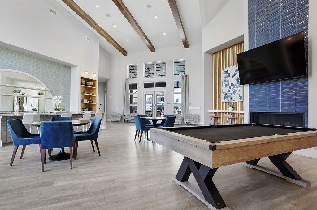 Open, airy modern lobby with pool table, blue chairs, and a wall-mounted TV.