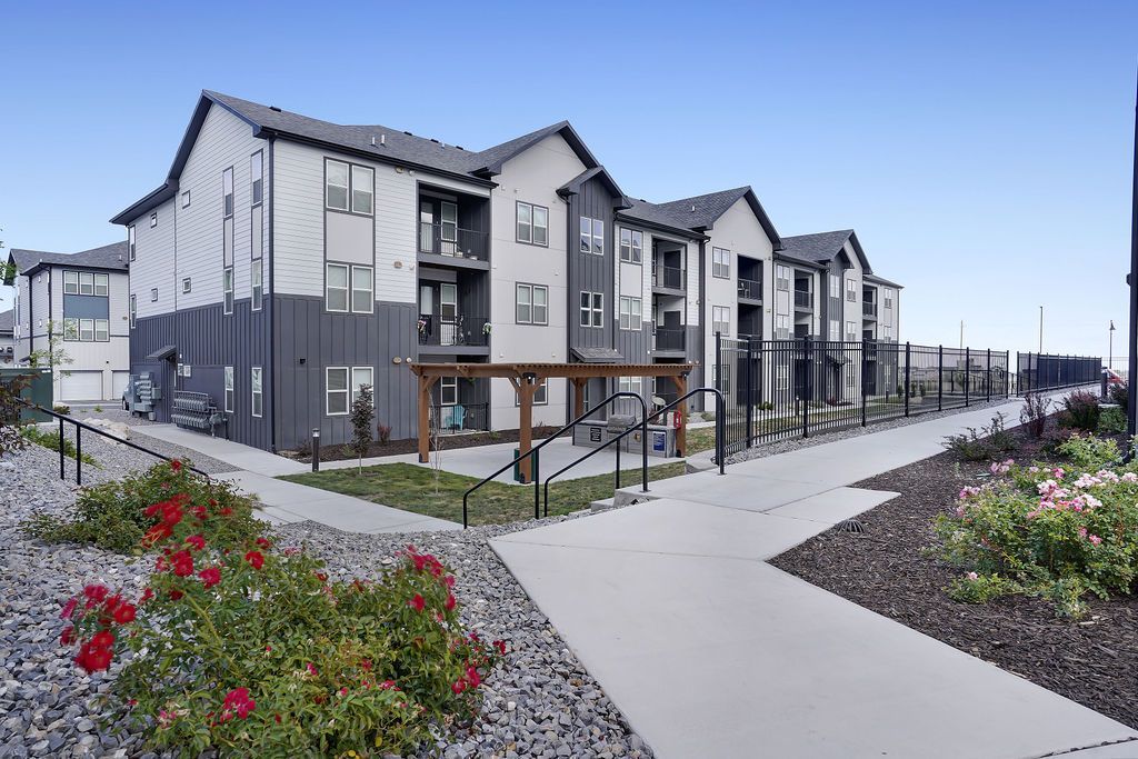 Exterior view of a modern apartment complex with multiple buildings, walkways, and landscaped grounds.