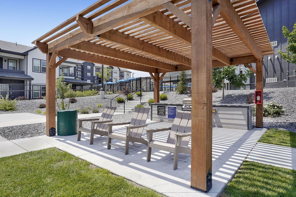 Wooden pergola with a seating area in a landscaped apartment community courtyard.