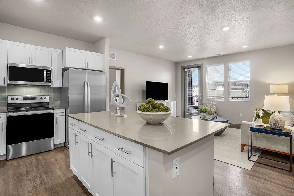 Bright modern kitchen with white cabinets, stainless steel appliances, and a large island.