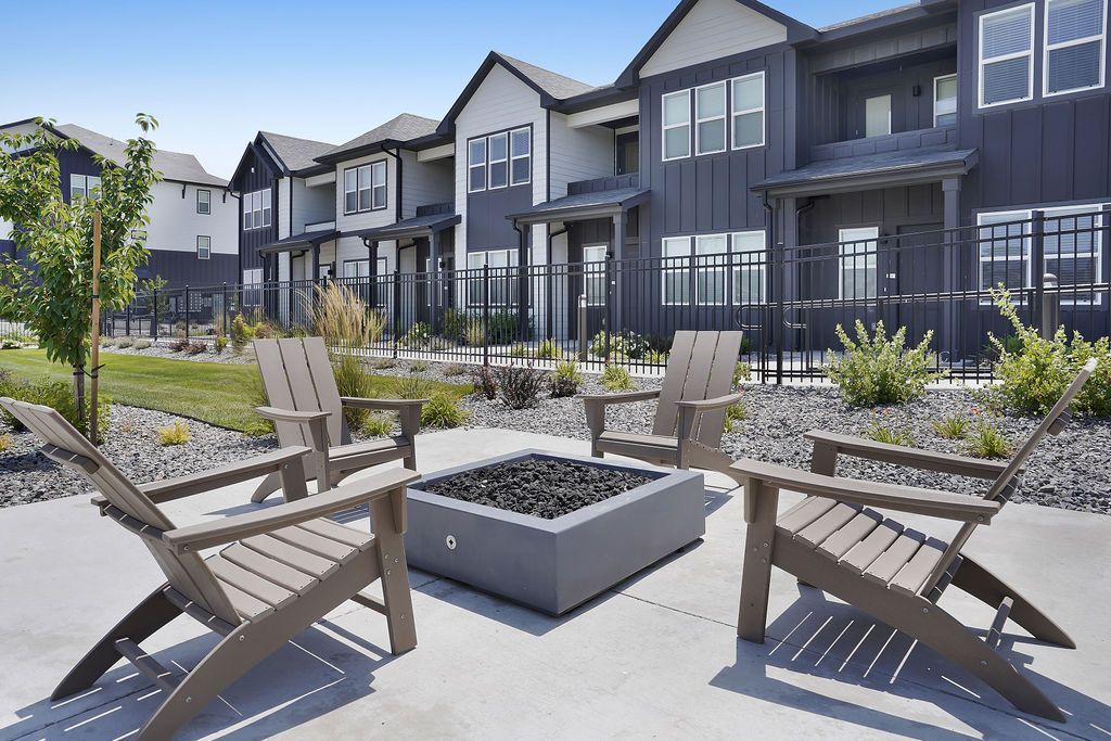 Outdoor community courtyard with a square fire pit and four surrounding chairs.