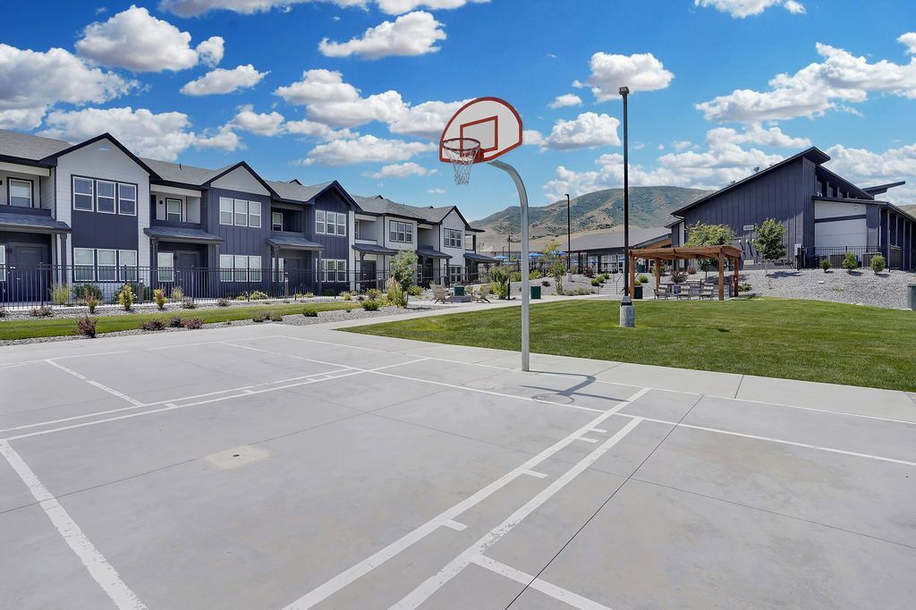 Outdoor basketball court with row of townhome-style buildings and landscaped lawn.