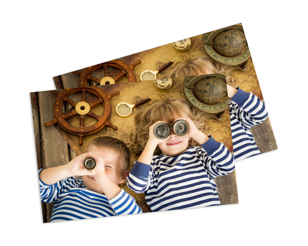 Two children in striped shirts looking through binoculars and magnifying glasses over a map with nautical decor
