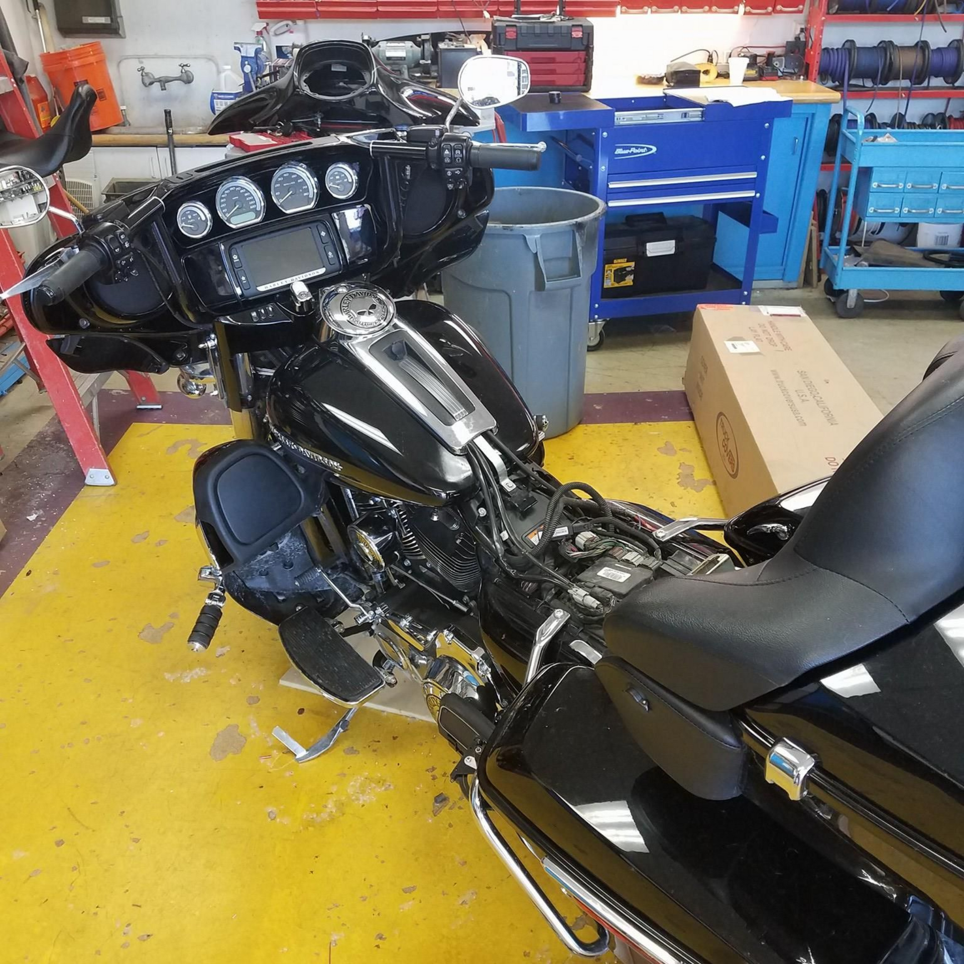 Black motorcycle in a repair shop with tools and a toolbox in the background.