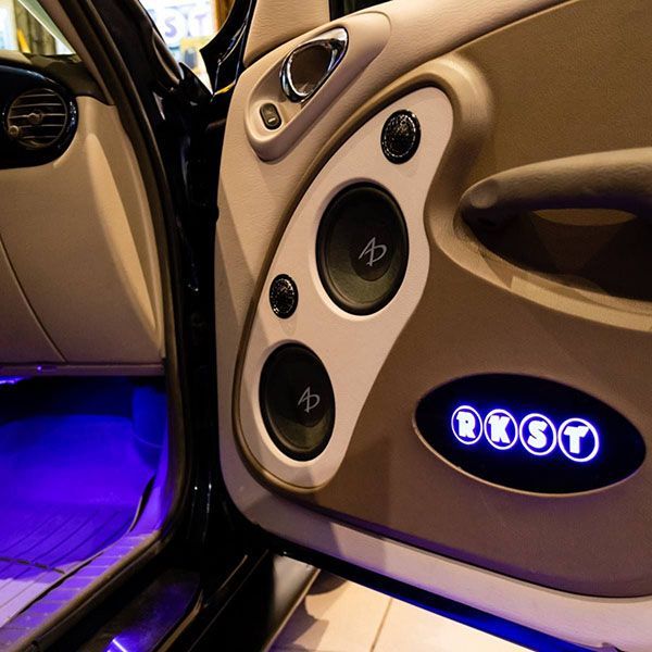 Car door with custom audio system; beige and white paneling, speakers, blue LED lighting, and 