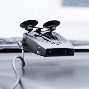 Black radar detector mounted on a car dashboard with a suction cup, showing illuminated