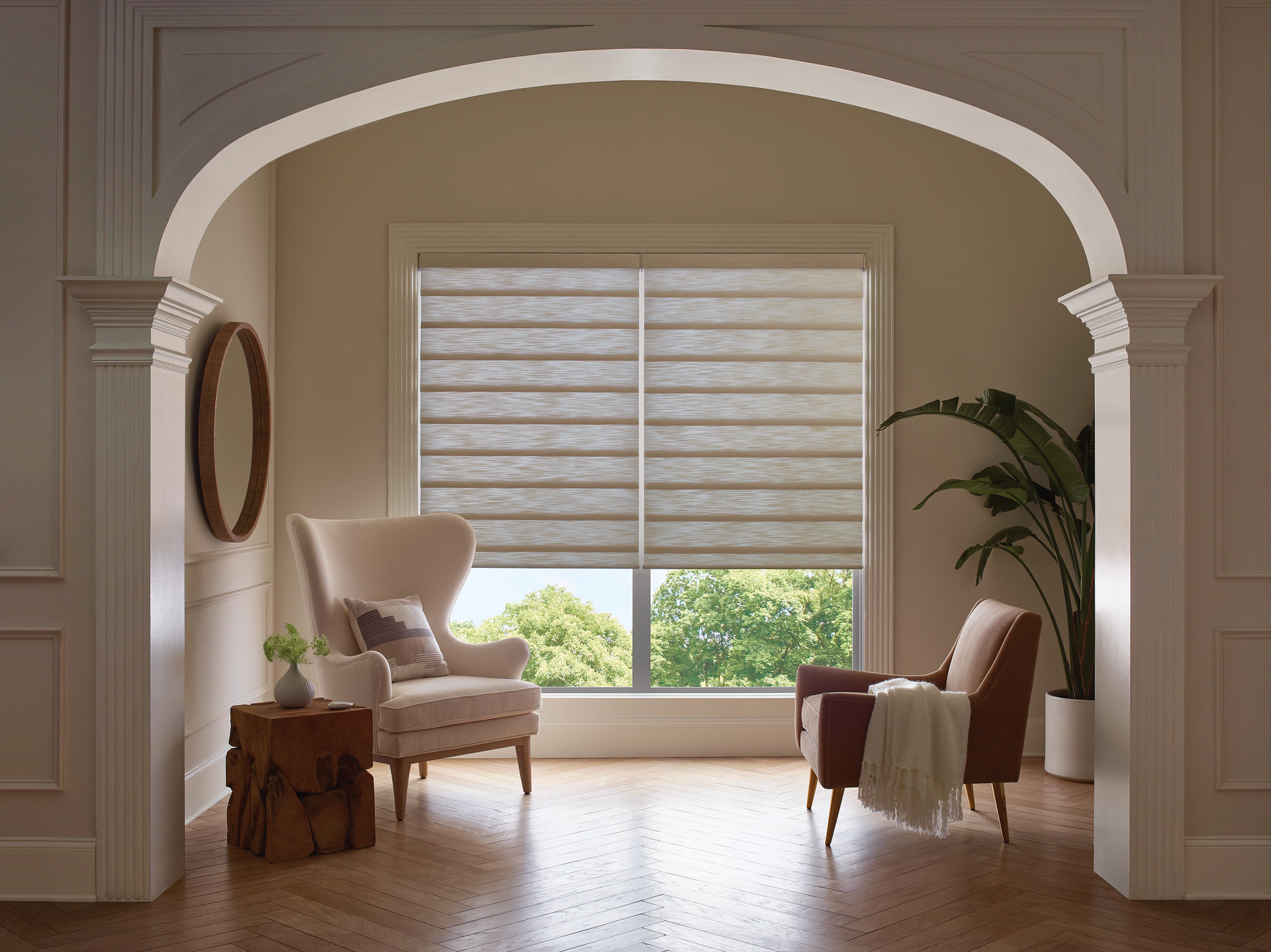 Elegant living room with arched doorway, white chairs, wooden table, and large window with blinds