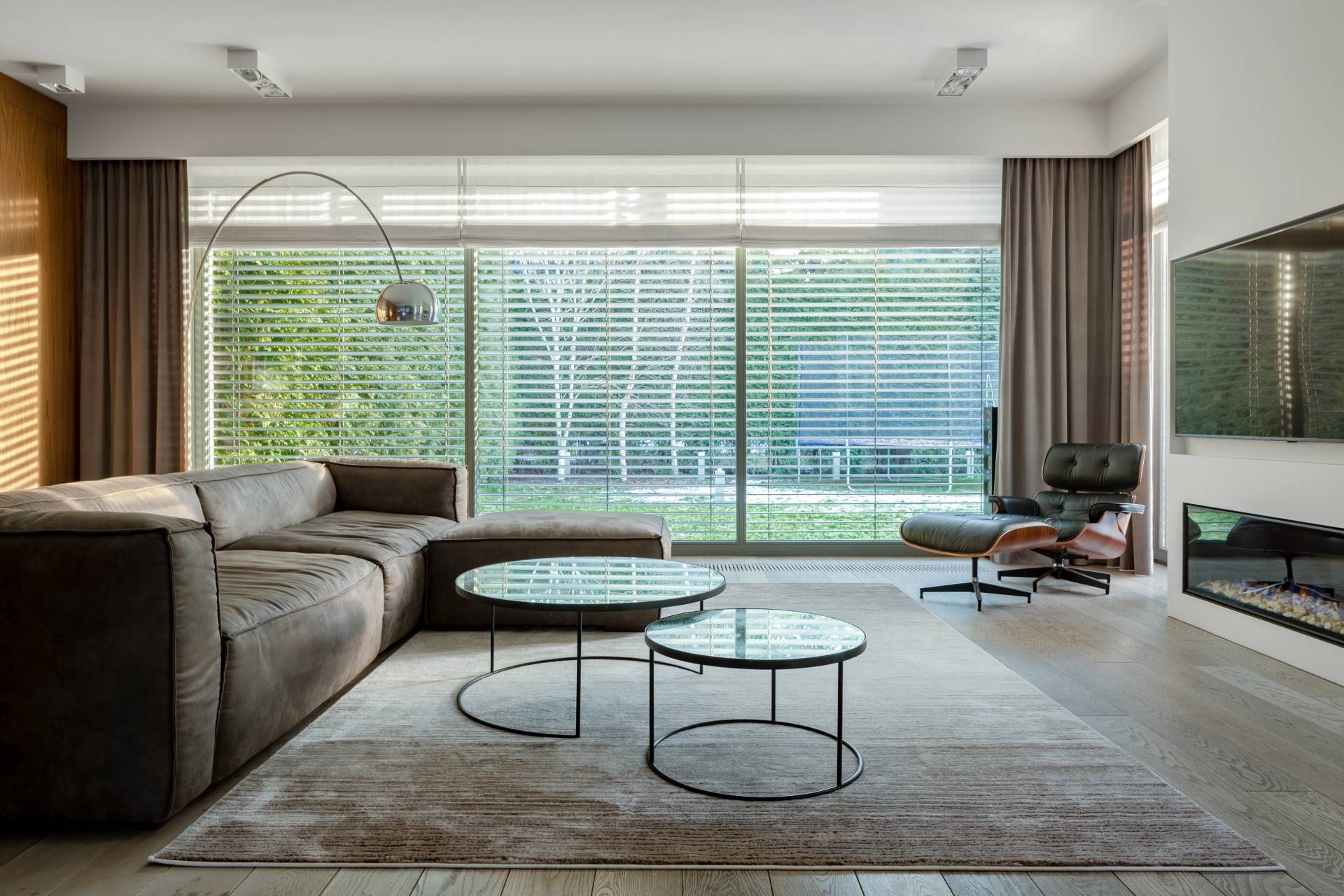 A chic living room with curated layers of drapes and blinds, a 2026 window treatment trend