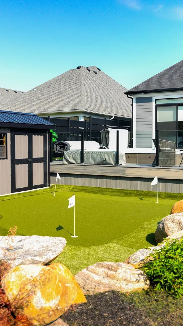 There is a putting green in the backyard of a house.