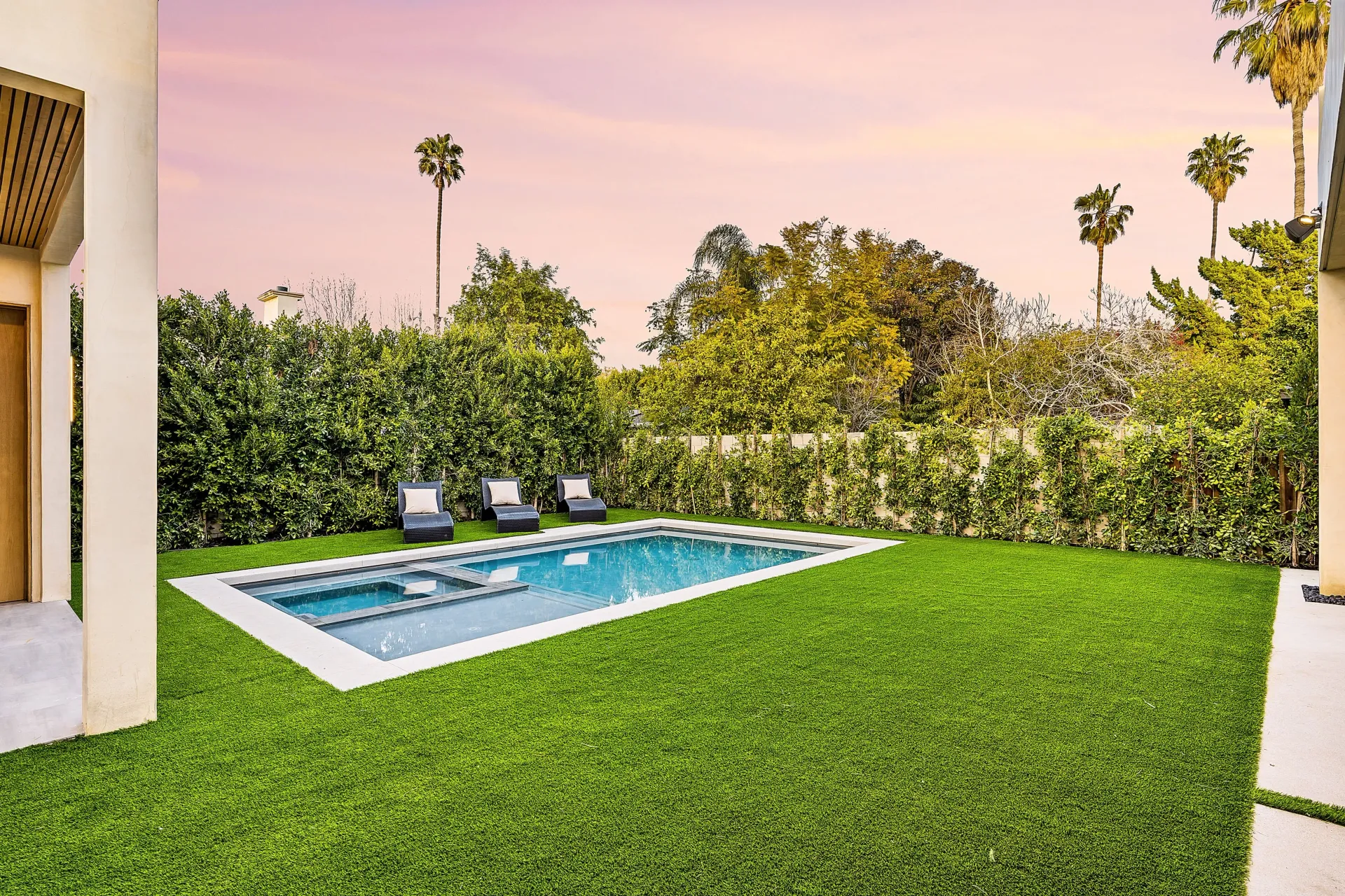 There is a large swimming pool in the backyard of a house.
