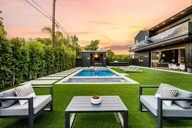 There is a large swimming pool in the backyard of a house.