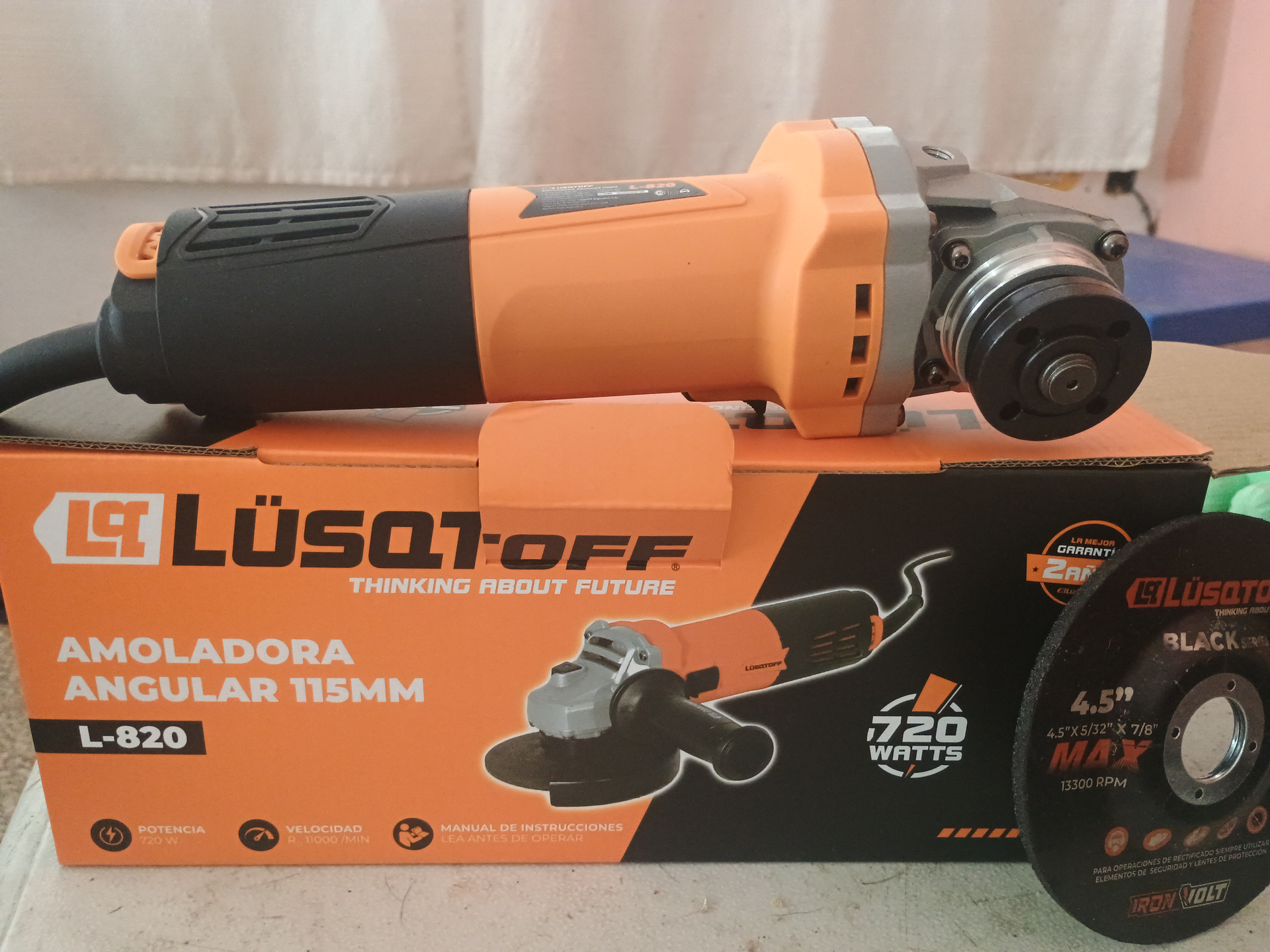 Amoladora angular naranja y negra con caja y disco de amolar.