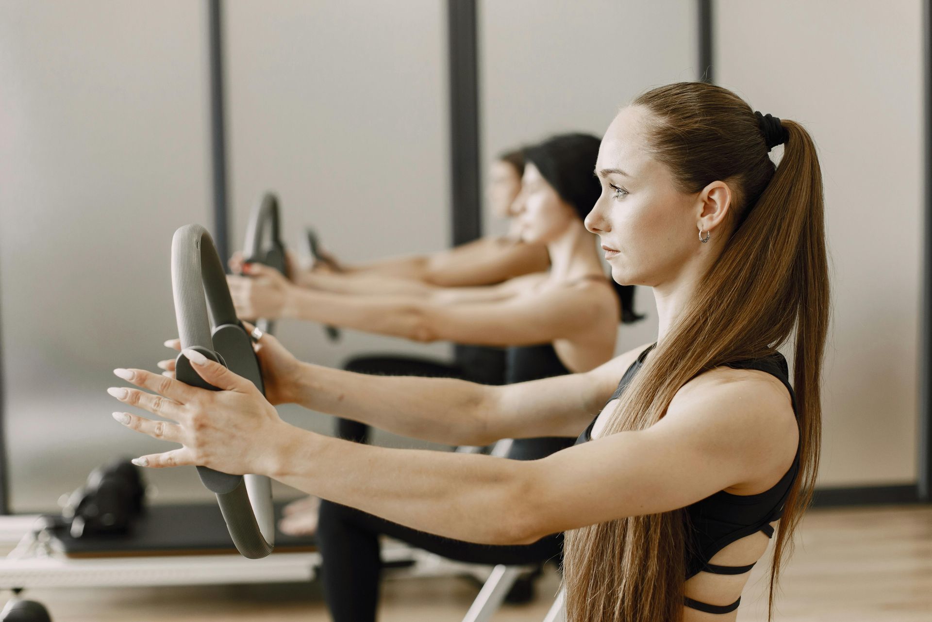 Group mat Pilates class using Pilates rings for upper body strength exercises.