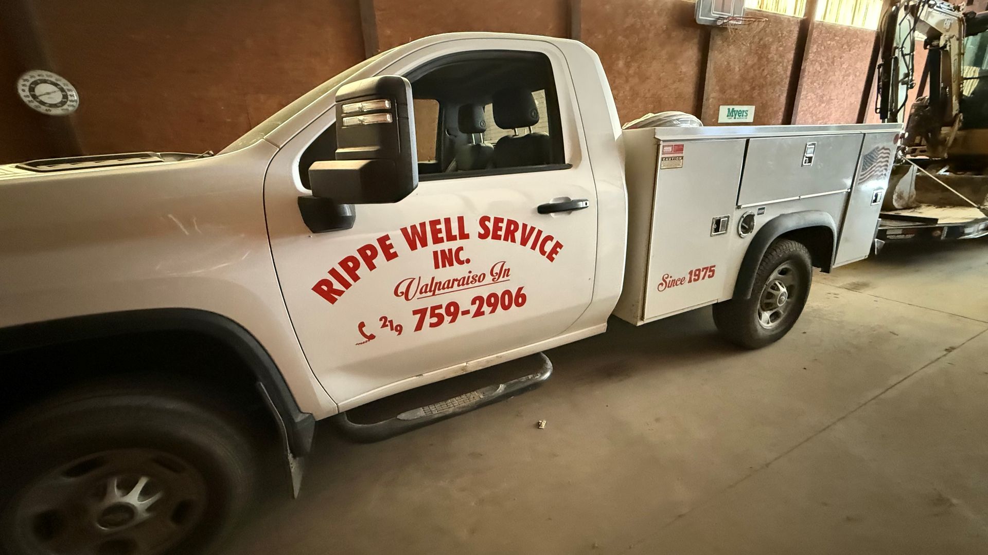 White work truck with "Rippe Well Service Inc." logo, parked inside a building.
