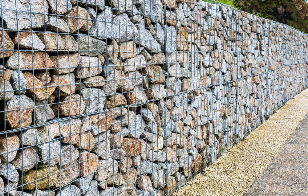 Gabion Wall Filled With Light Gray and Brown Stones — Macca's Dynamic Earthworks in Tolga, QLD