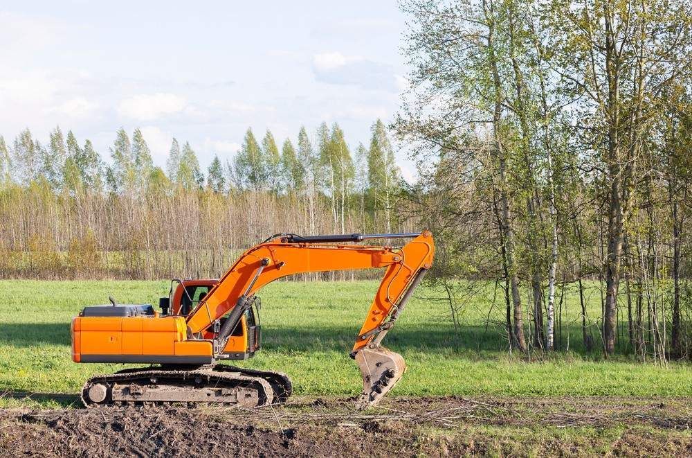 Orange Excavator on Green Field — Macca's Dynamic Earthworks in Kuranda, QLD