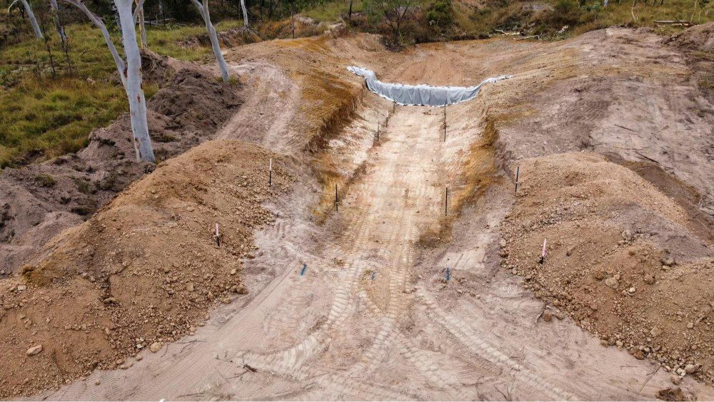 A Red Tractor Sits Near a River Bank — Macca's Dynamic Earthworks in Tolga, QLD