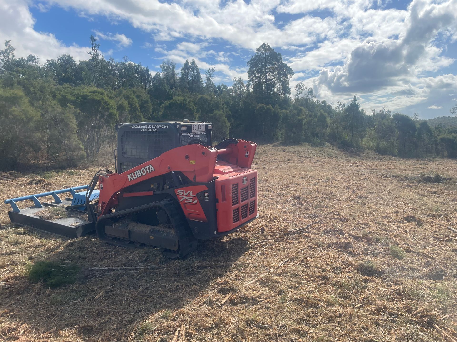 Red Kubota Skid Steer With a Mulching Head Clearing a Wooded Area — Macca's Dynamic Earthworks in Tolga, QLD
