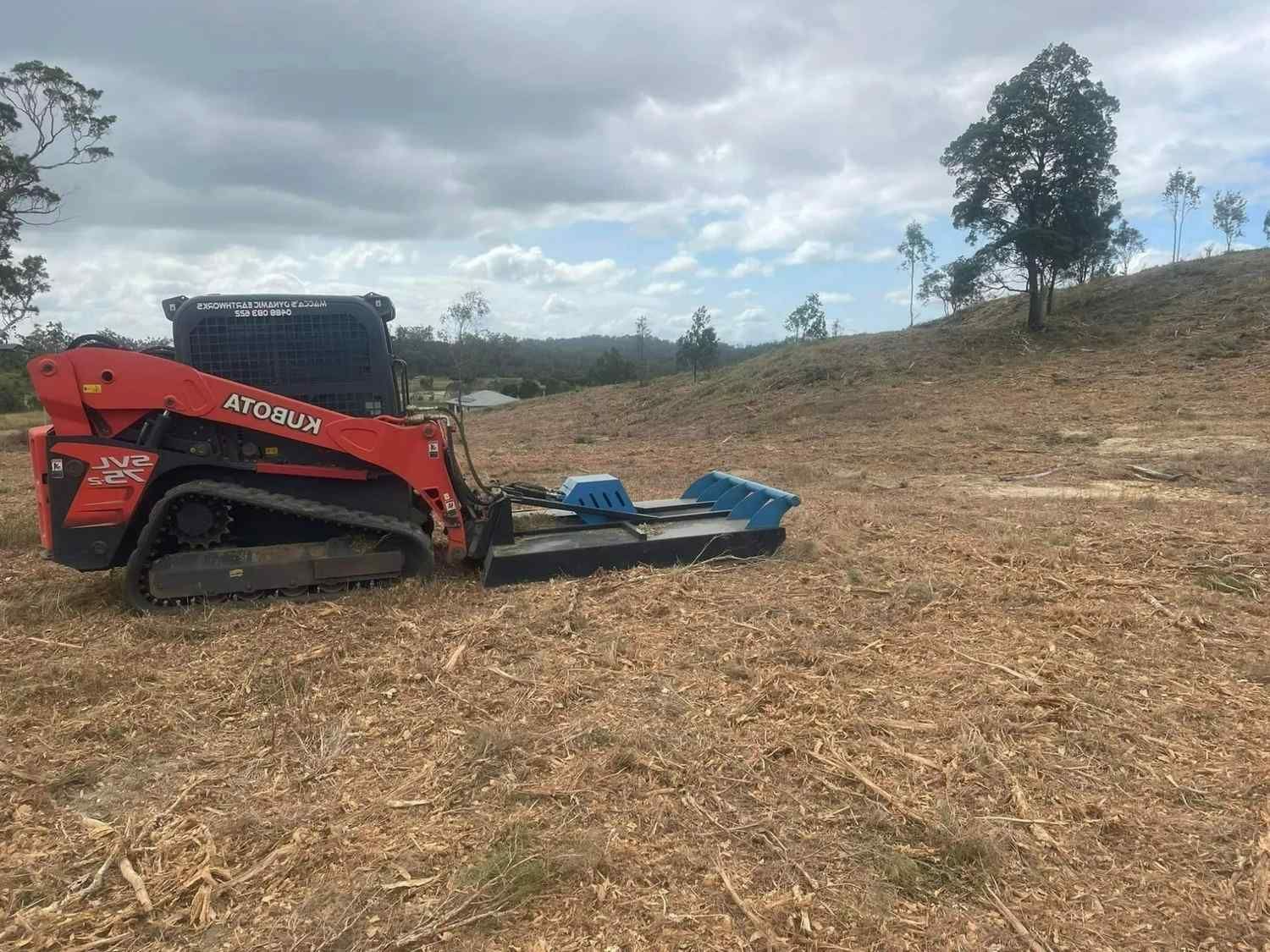 Red Skid Steer with A Brush Cutter Clearing a Field — Macca's Dynamic Earthworks in Atherton, QLD
