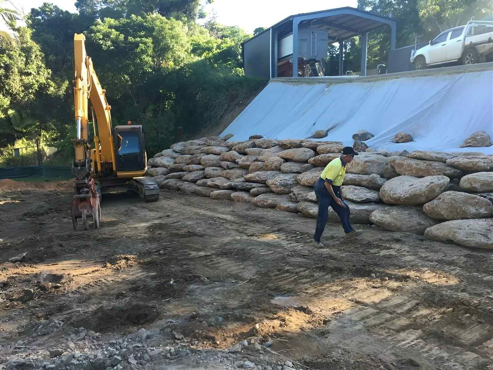 A Worker Building a Stone Retaining Wall — Macca's Dynamic Earthworks in Tablelands, QLD