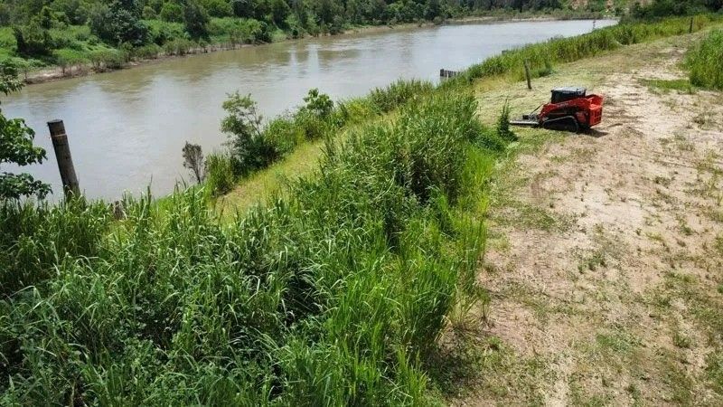 A Red Tractor Sits Near a River Bank — Macca's Dynamic Earthworks in Tolga, QLD