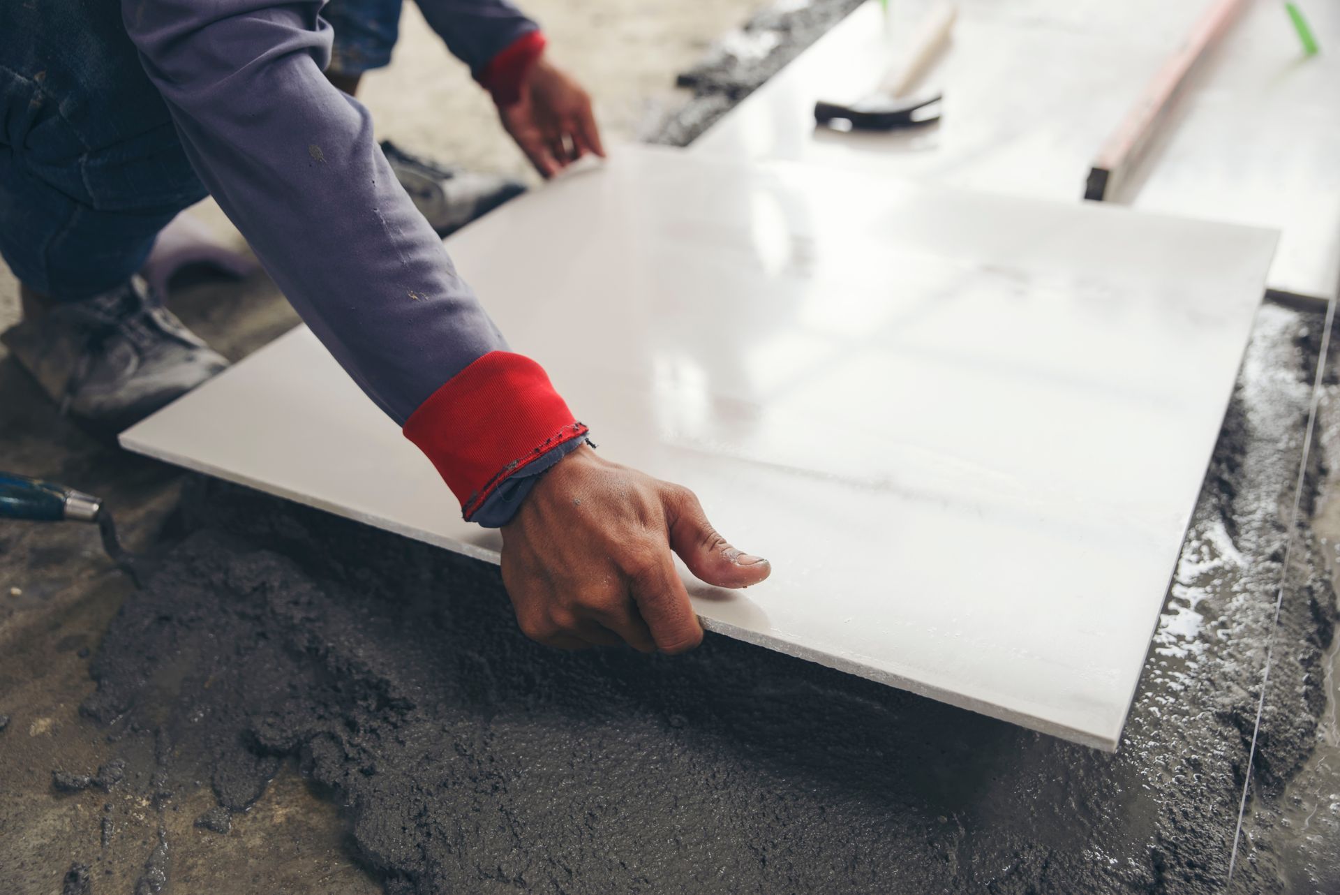 A man is laying a tile on the floor.