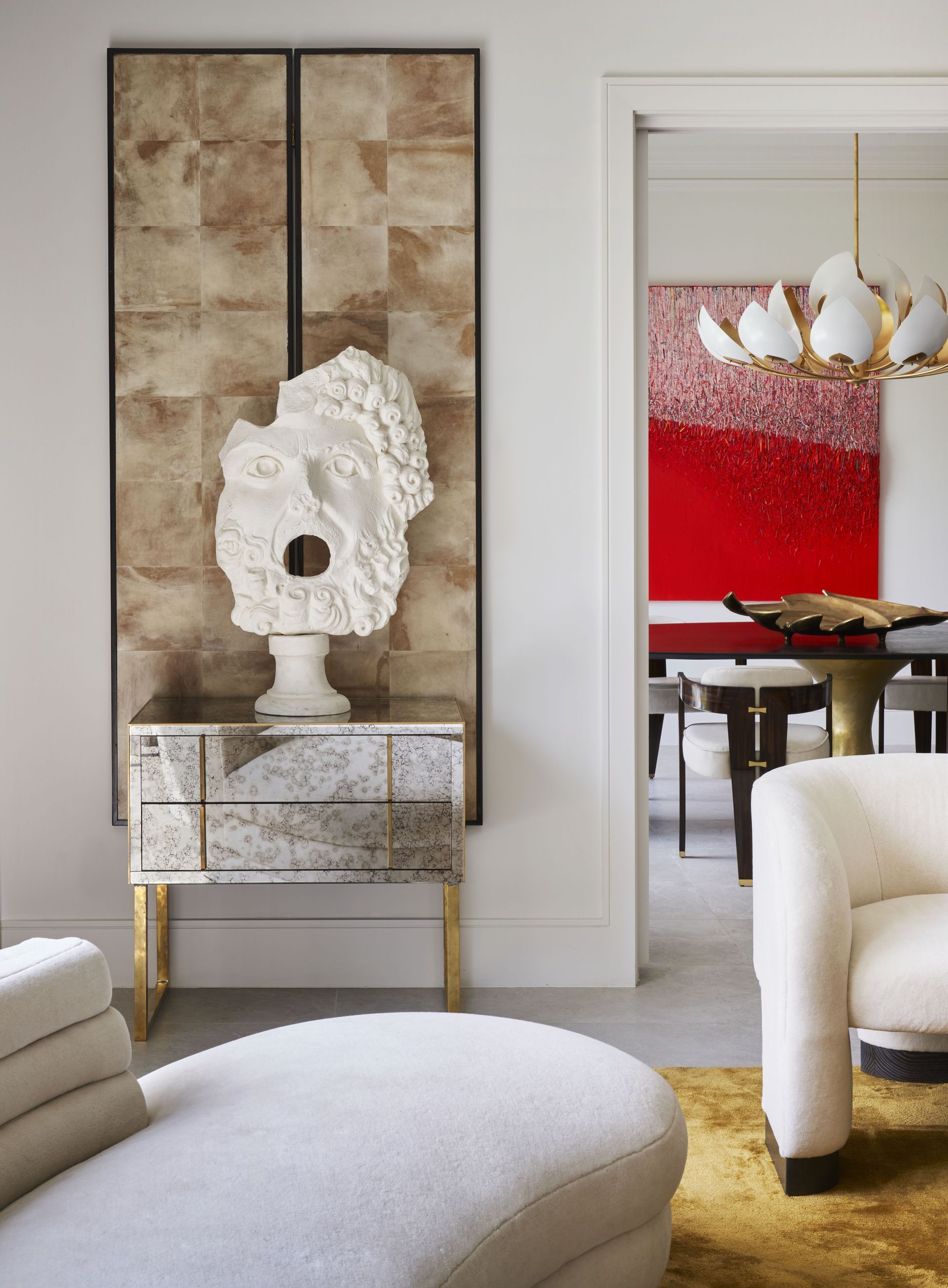 a living room with white furniture and a statue on the wall