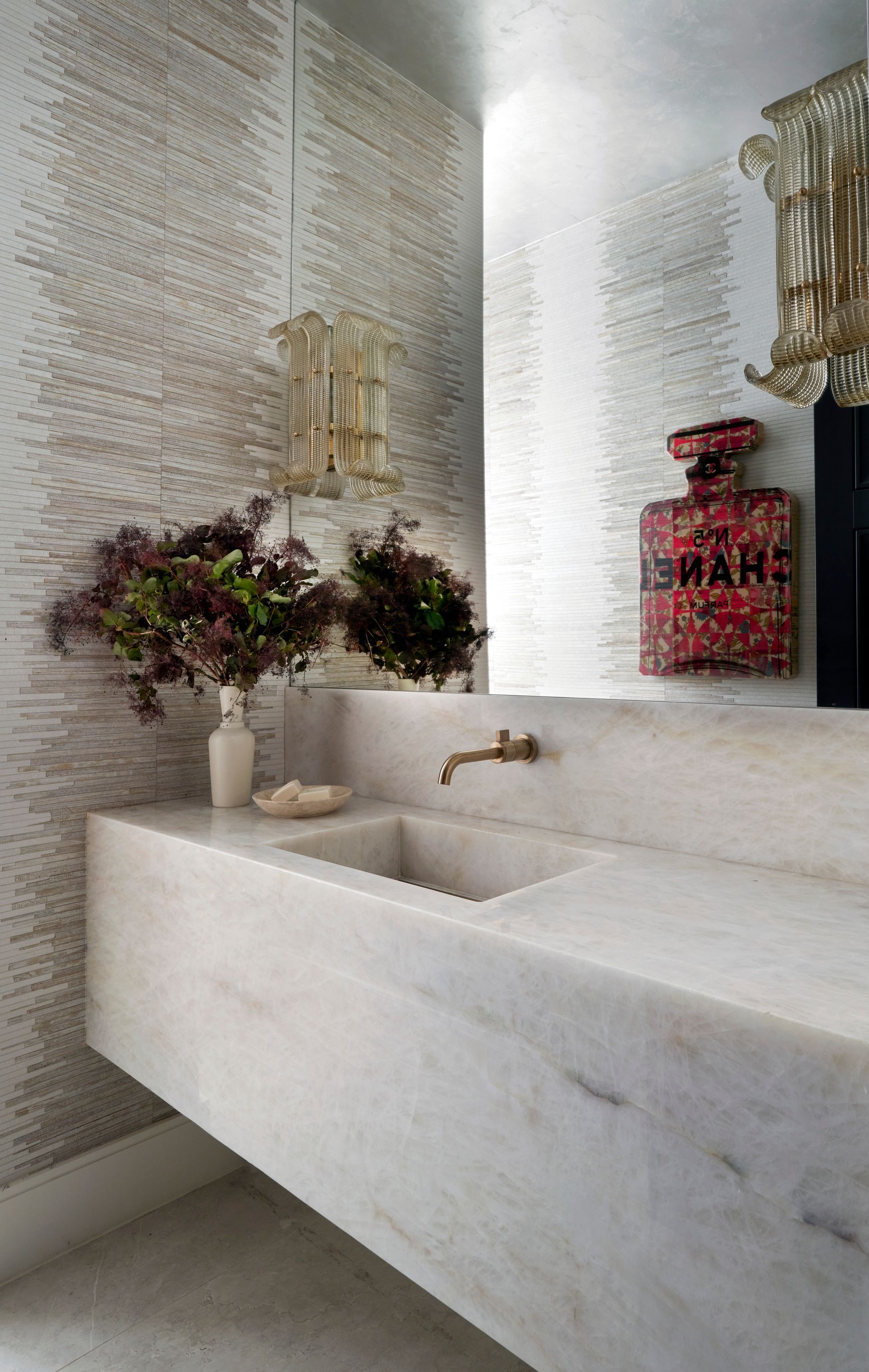 a bathroom with a sink and a bottle of perfume on the wall .