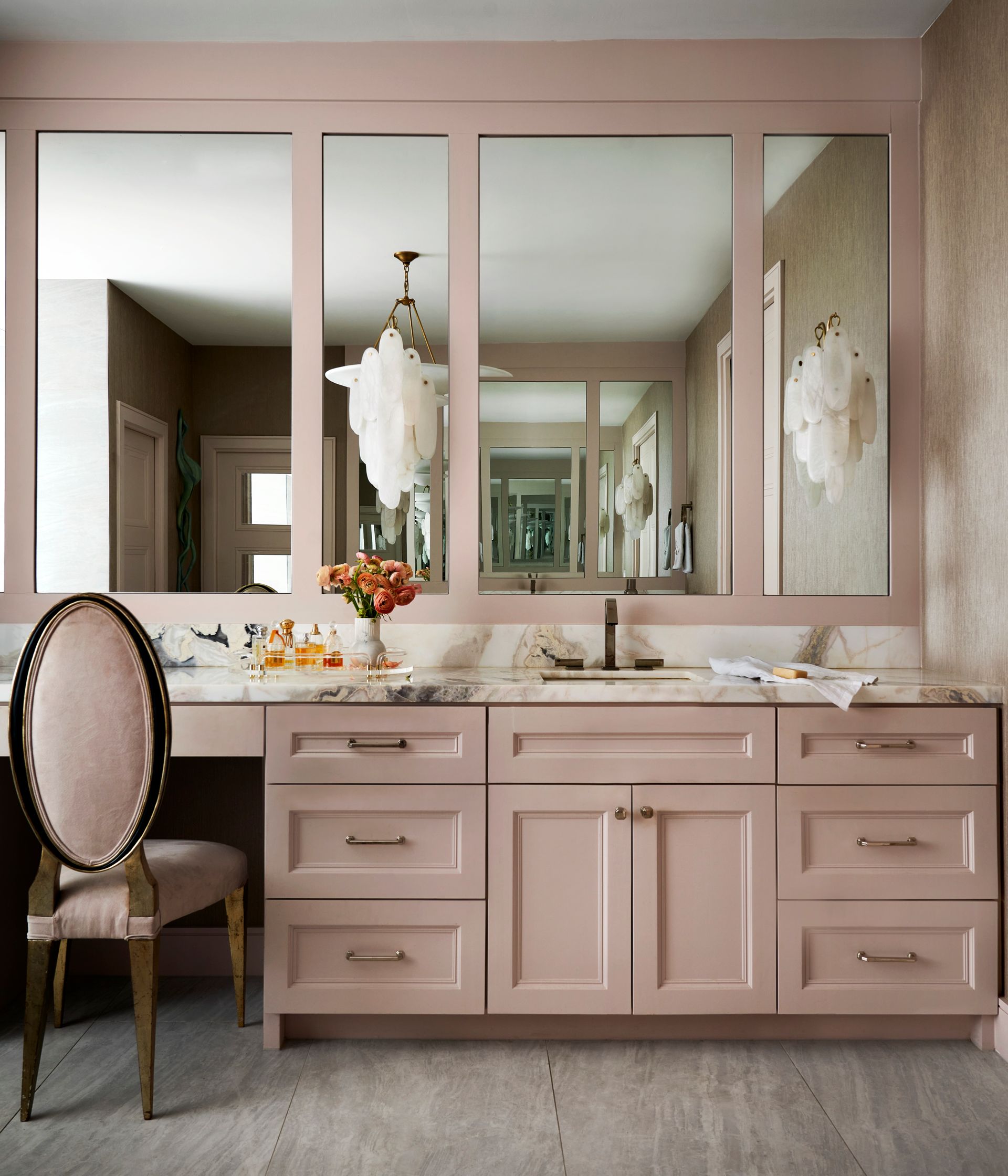 a bathroom with pink cabinets and a large mirror