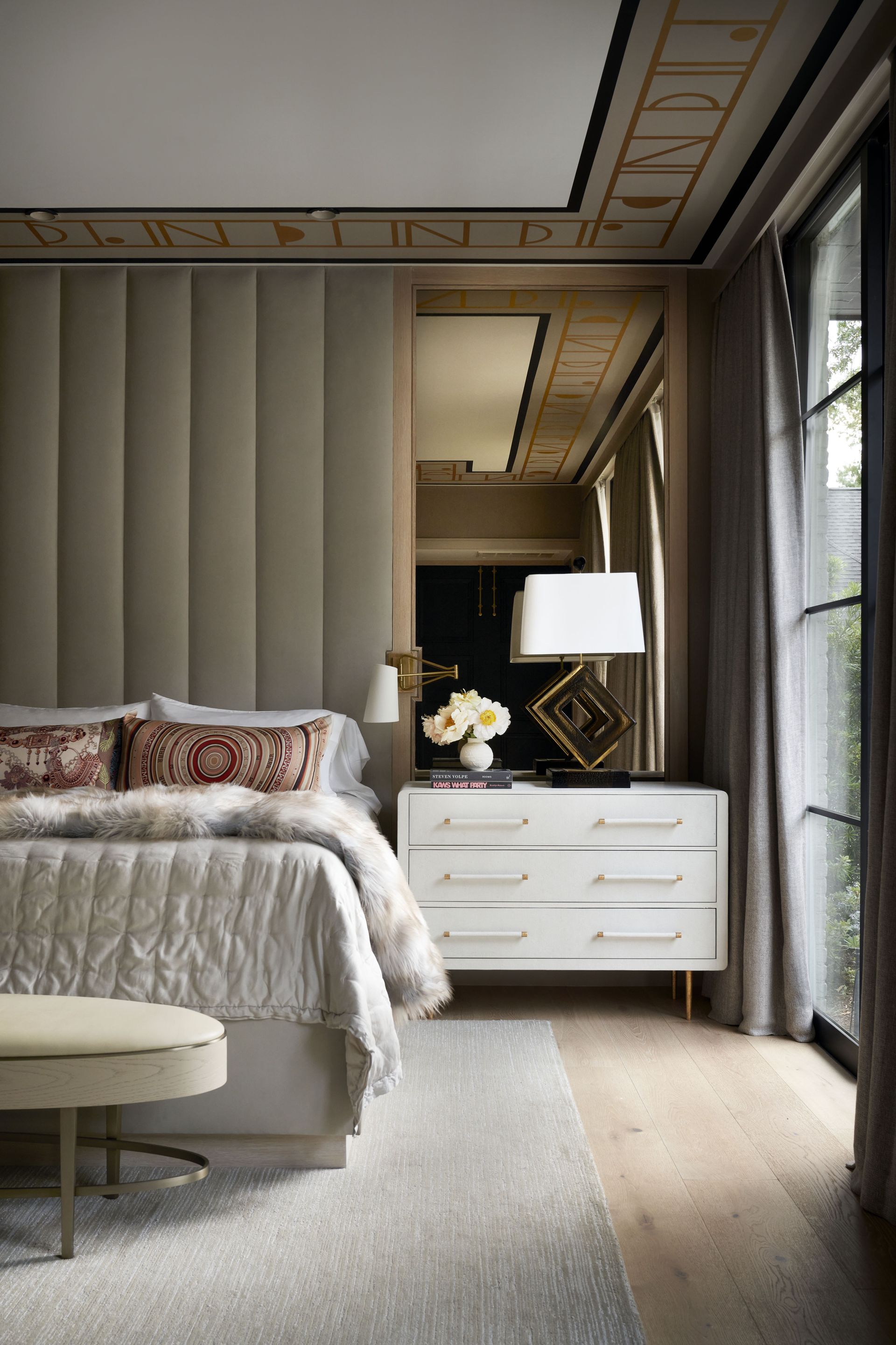 a bedroom with a bed , dresser , nightstand and mirror .