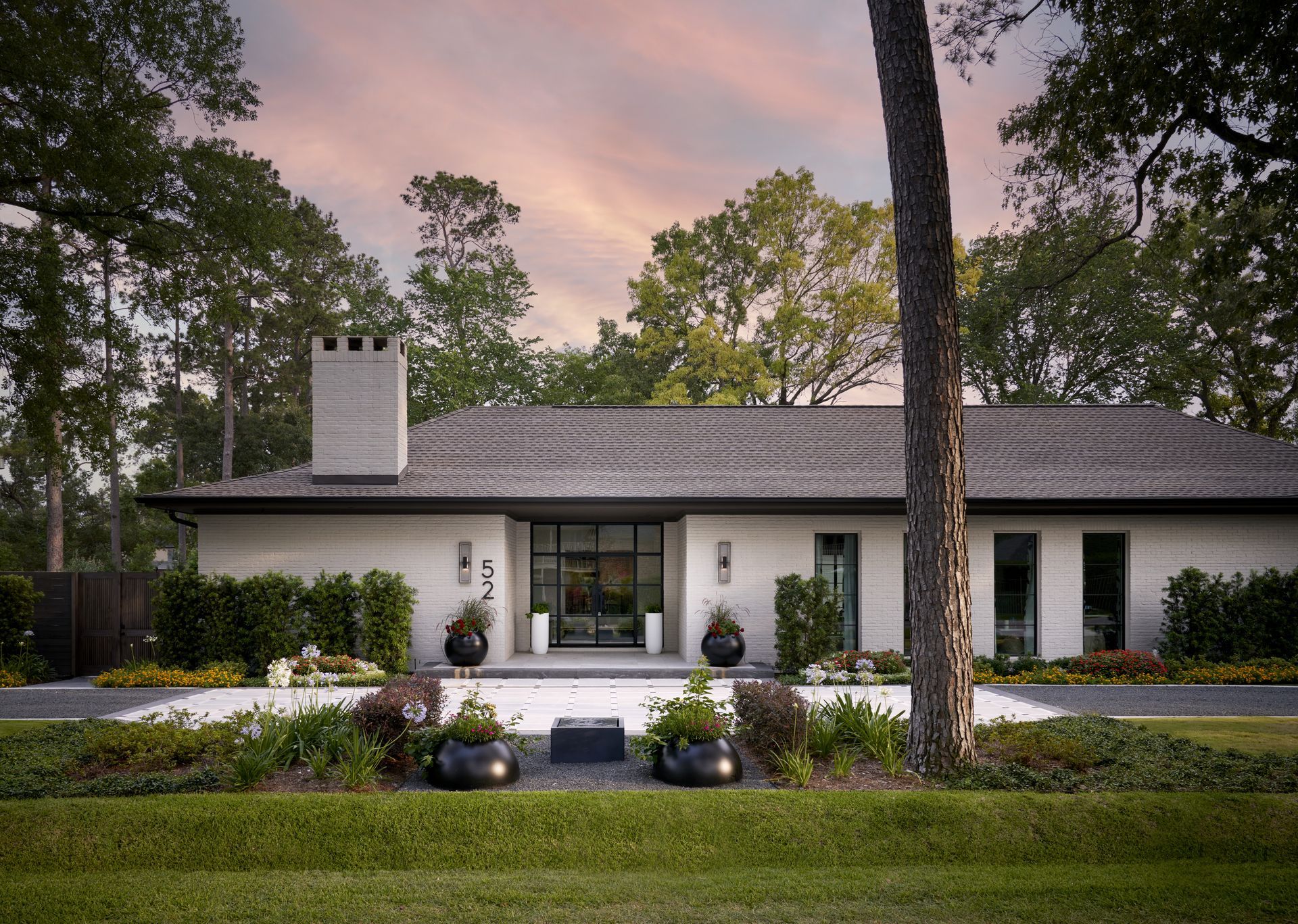 a white house with a gray roof is surrounded by trees