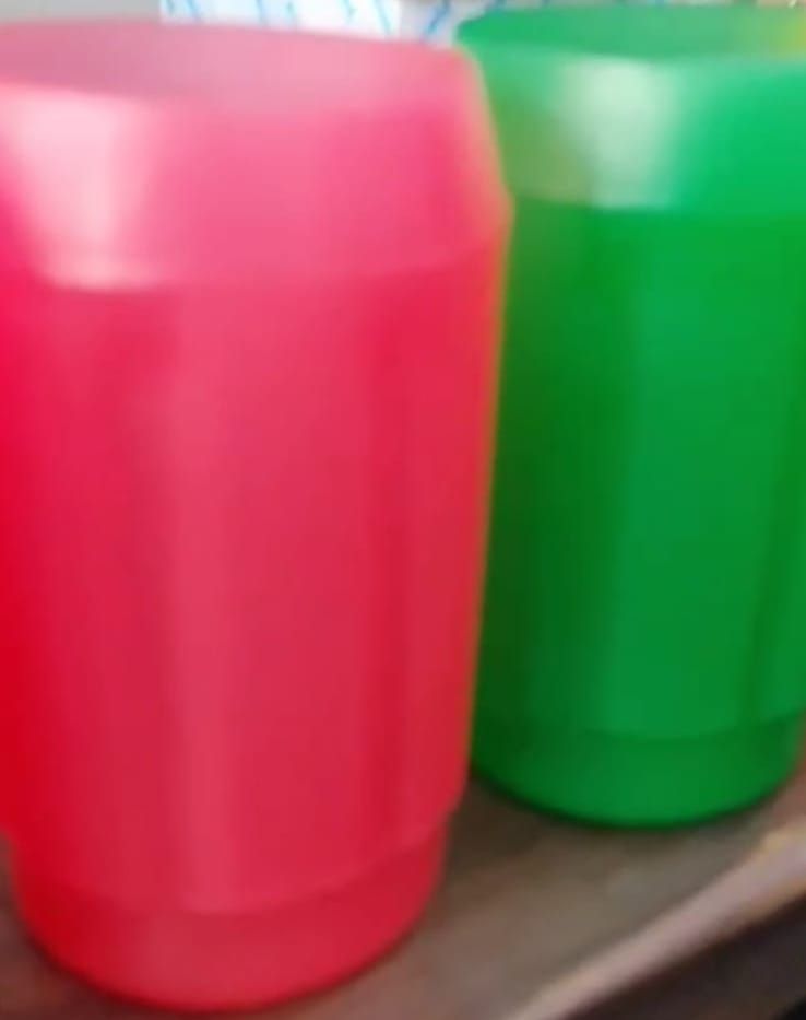 Two red and green plastic buckets are sitting on a wooden table.