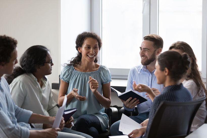 A group of people are sitting in a circle talking to each other.