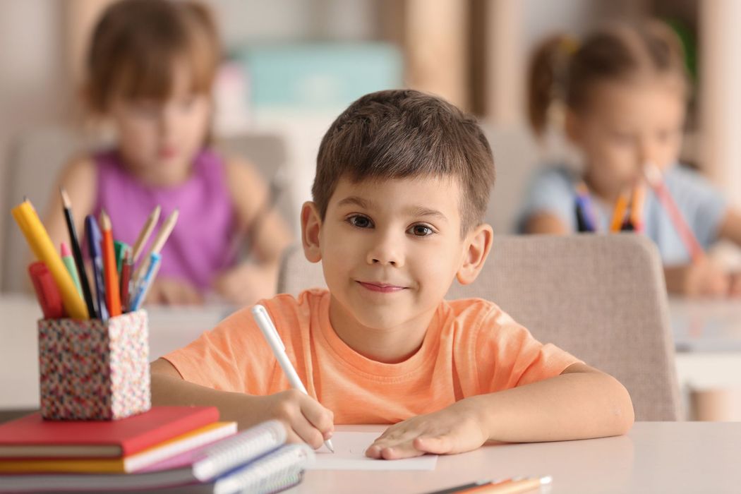child smiling in class while colouring a drawing