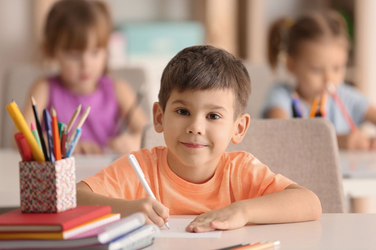 bambino sorridente in classe mentre colora