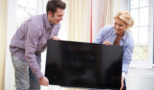 Couple carrying TV in Nelson