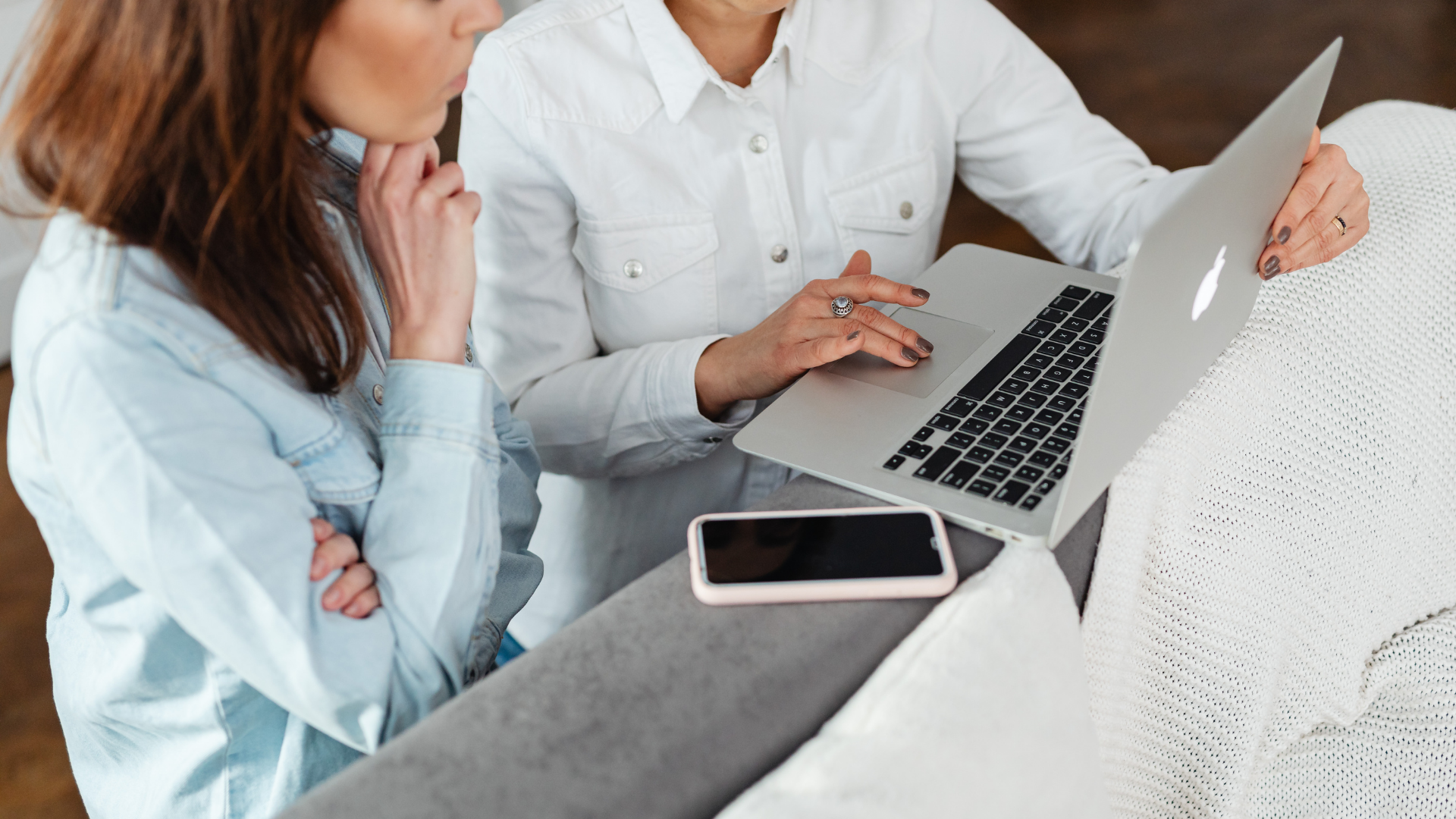 Person in tan blazer using calculator and laptop, working on documents at a desk