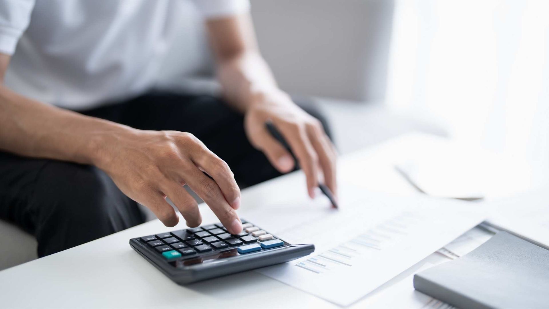 a person using a calculator and writing with pen and paper 