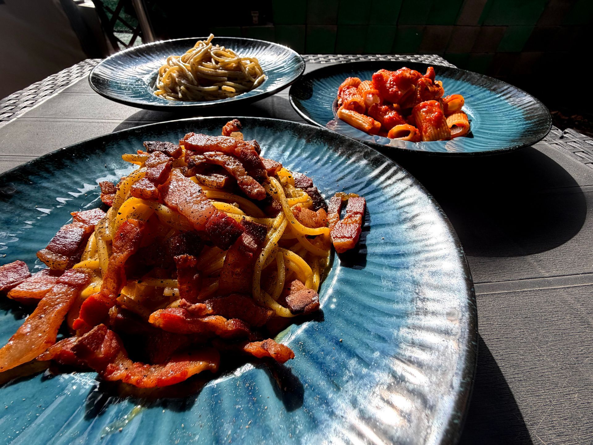 Piatti di pasta: uno con pancetta, uno con sugo rosso e il terzo con sugo verde.