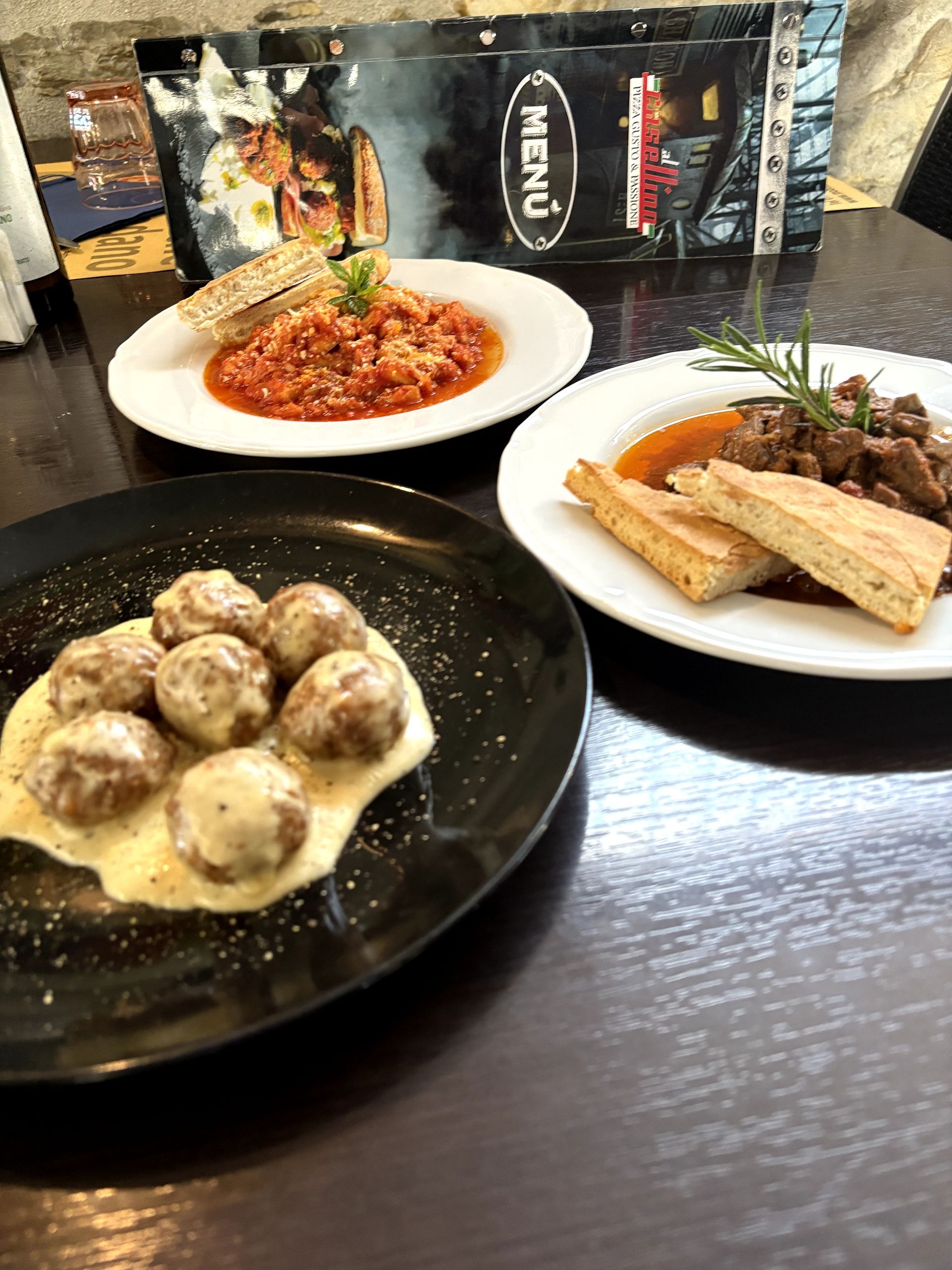 polpette, uno stufato con pane. Sullo sfondo un menu.